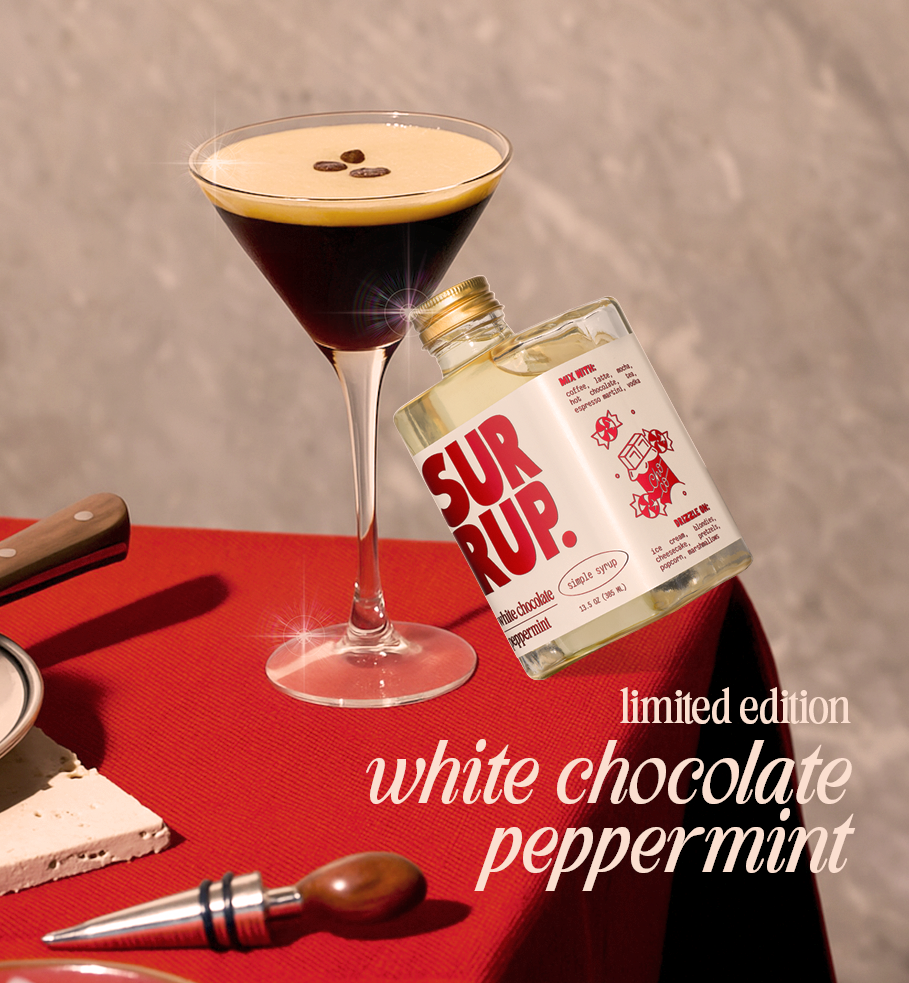 Cocktail with a bottle of 'Sur Rup' white chocolate peppermint syrup on a red tablecloth.